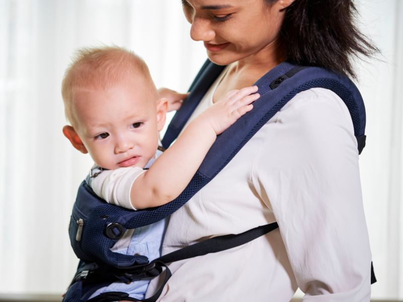 Mujer porteando a bebé en una mochila portabebés